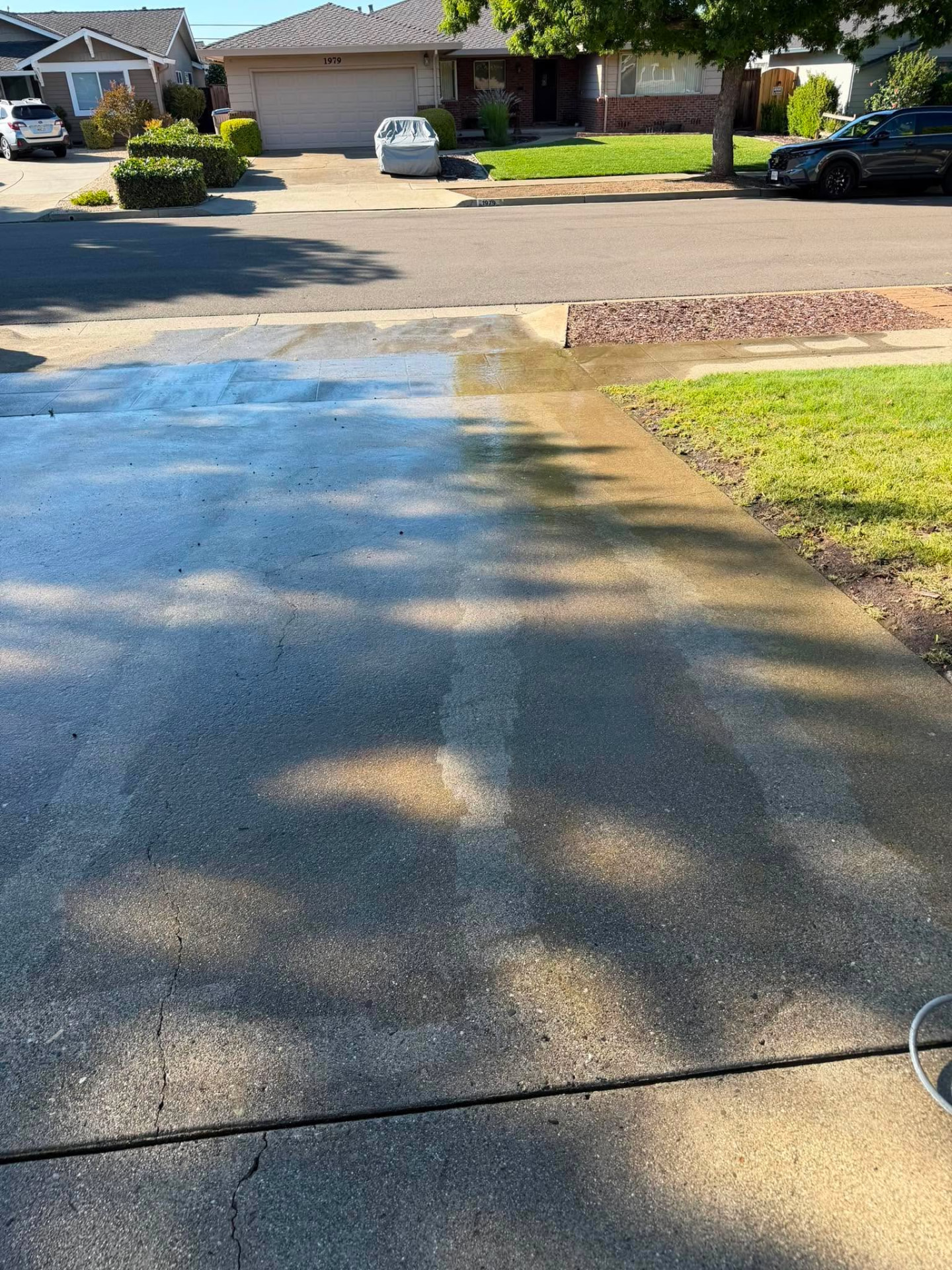 Driveway halfway through pressure washing showing the clean line