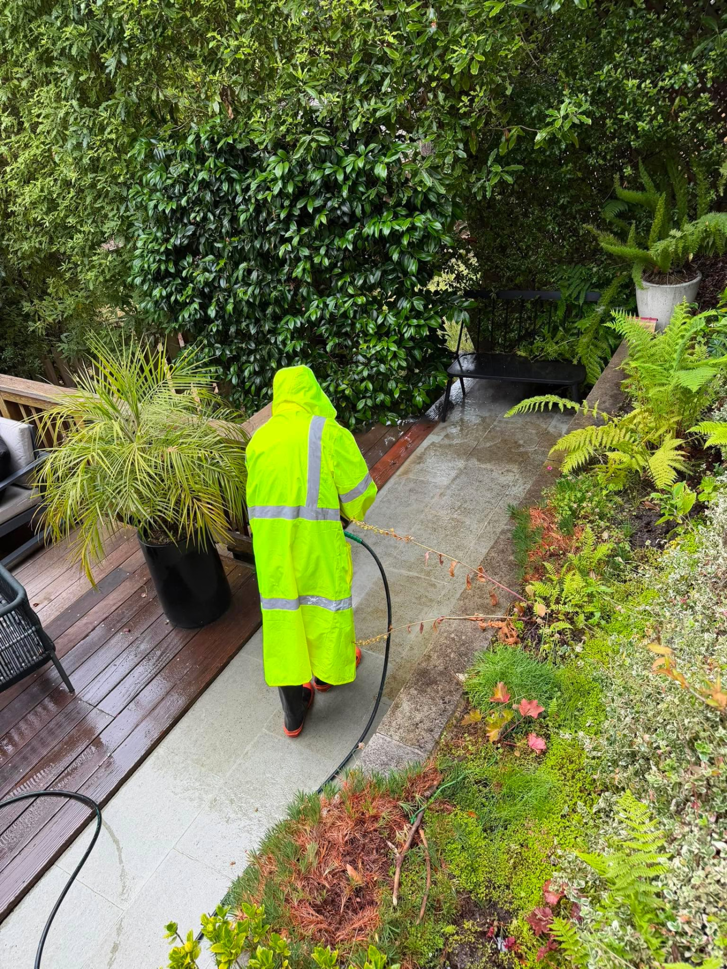 Crew member pressure washing a backyard stone patio